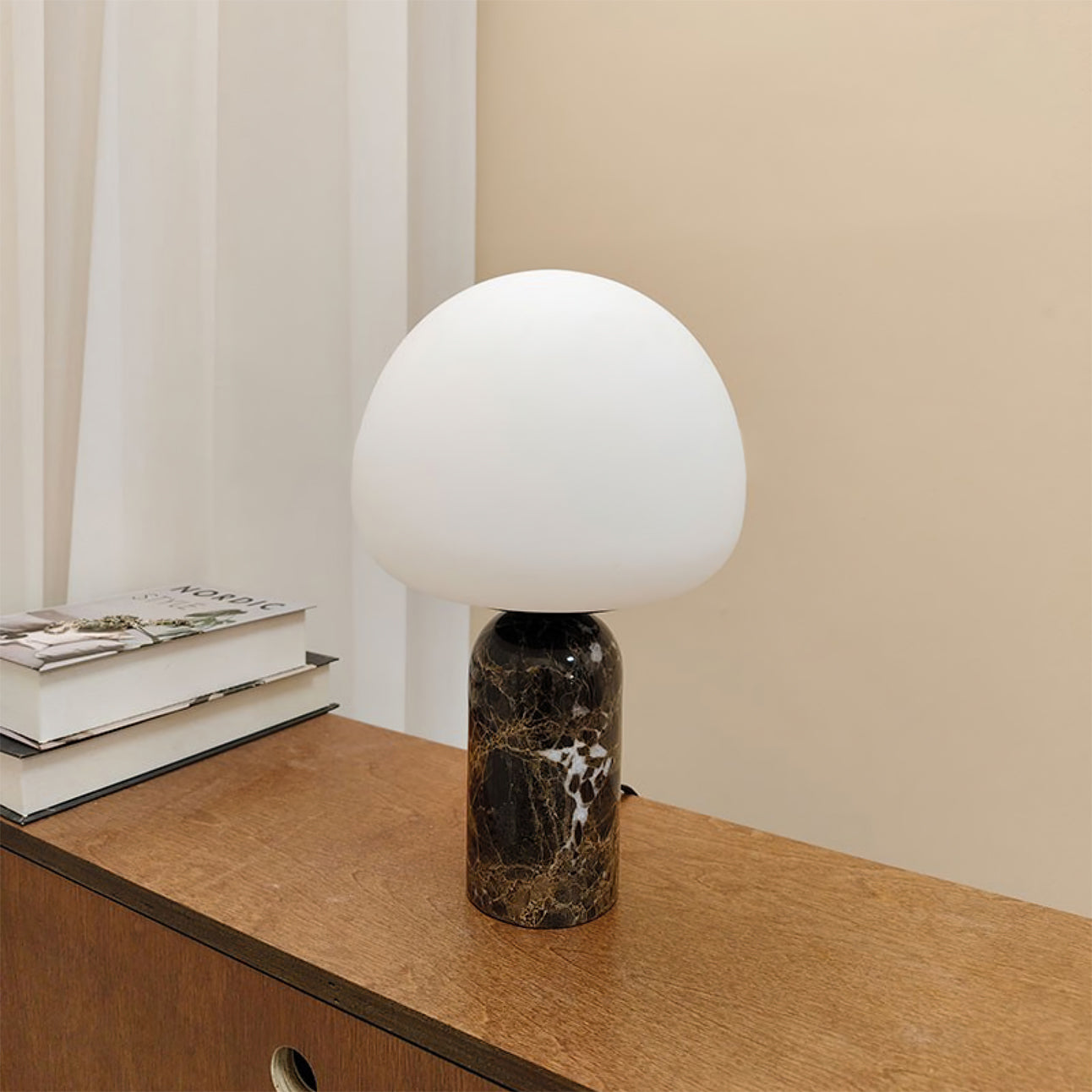 Kizu marble table lamp on bedroom dresser with stacked books, creating minimalist home decor