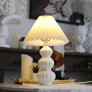 Illuminated Luna pleated table lamp on vintage home shelf, warm beige shade with soft diffused light, mid-century modern aesthetic