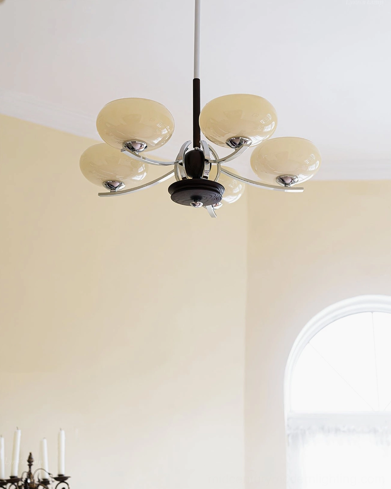 Five-light mid-century glass chandelier in interior space with arched window and candlestick decor - front low angle perspective showing dark wood fixture and cream shades