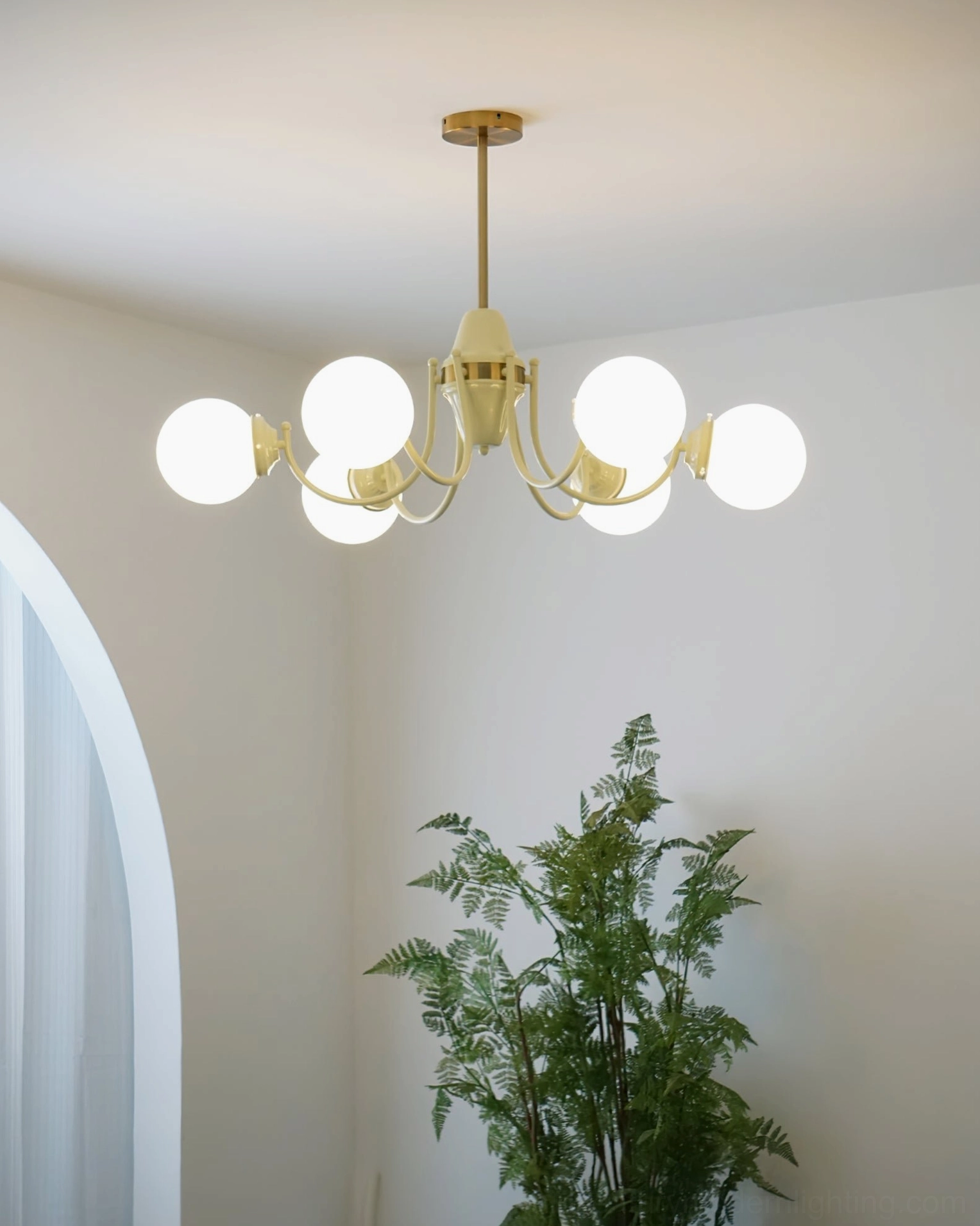 Six-head globe chandelier with illuminated milk glass shades and warm metal finish in modern interior