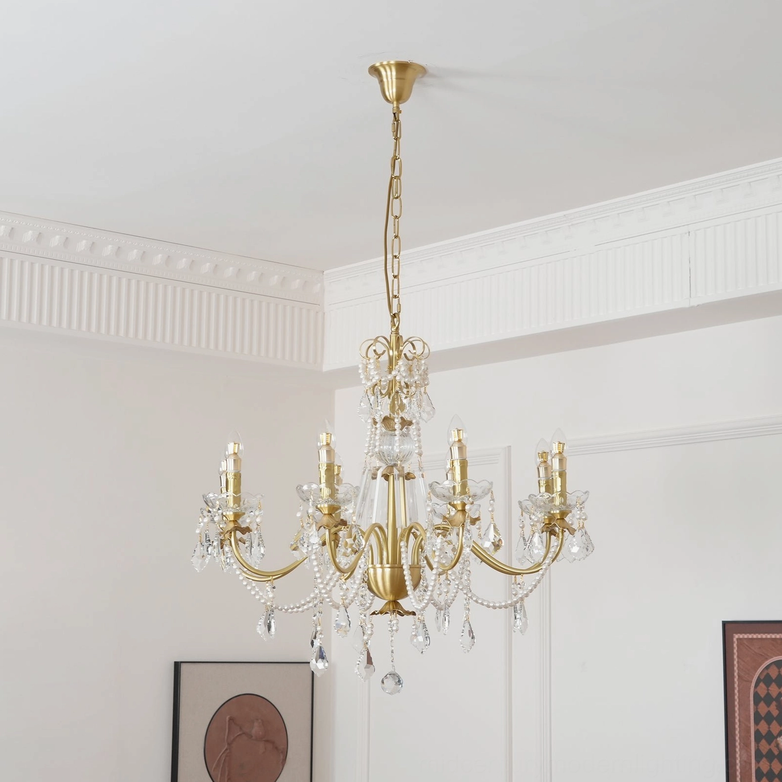 8-light brass and crystal chandelier with polished gold finish hanging in French room with wall artwork