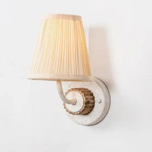 Abbey French Country wall light front overhead view with beige pleated shade and speckled base plate