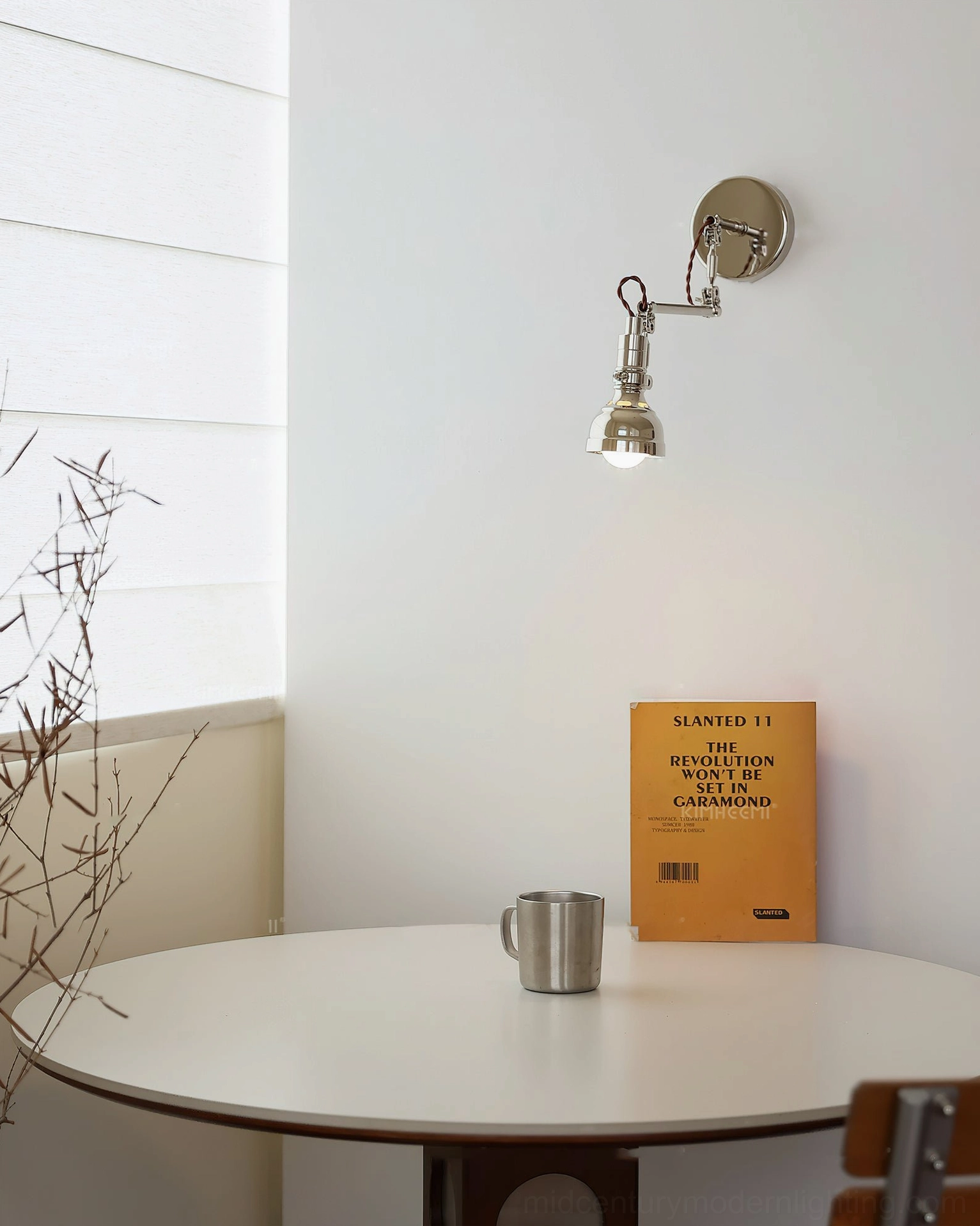 Compact swing arm wall lamp overhead view in dining nook setting, minimalist chrome fixture design