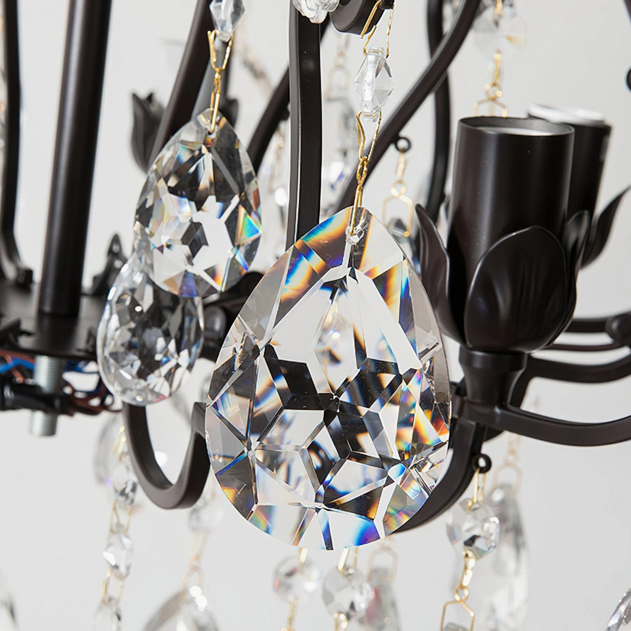 Macro close-up of Aeliana Crystal Chandelier showing black metal frame with teardrop faceted crystals and candle lamp sockets