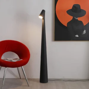 Black tapered floor lamp in contemporary living room setting, paired with red accent chair and modern wall art, side view