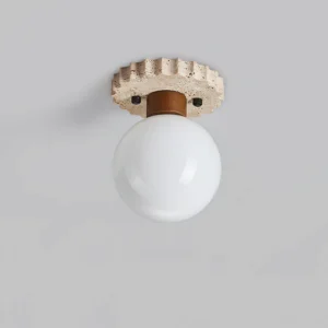 Overhead front view of spherical ceiling lamp with serrated porous travertine mounting base and white glass shade detail