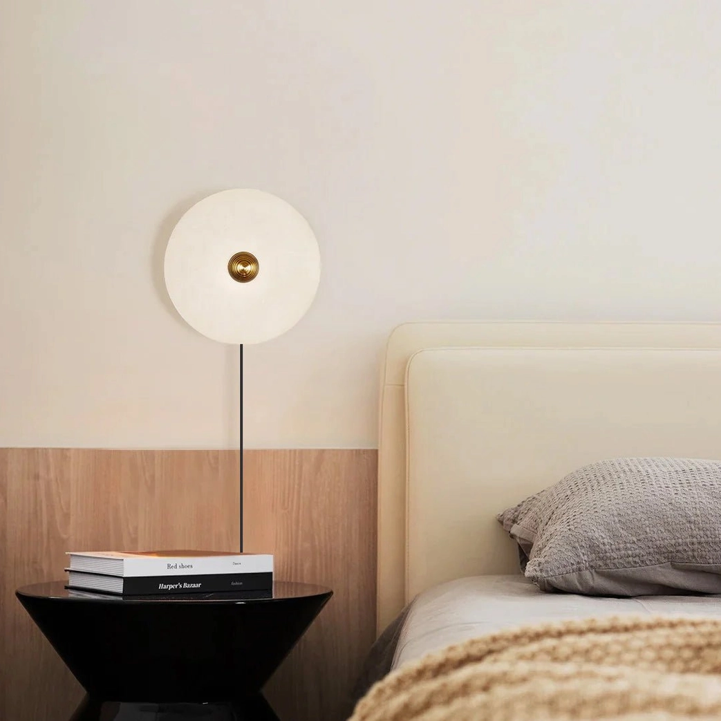 Alabaster bedside wall sconce creating cozy minimalist bedroom ambiance at eye level