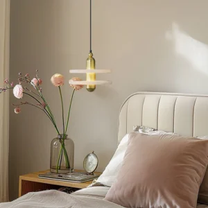 Brass tiered pendant lamp installed in modern master bedroom creating warm ambient lighting above nightstand in minimalist mid-century interior