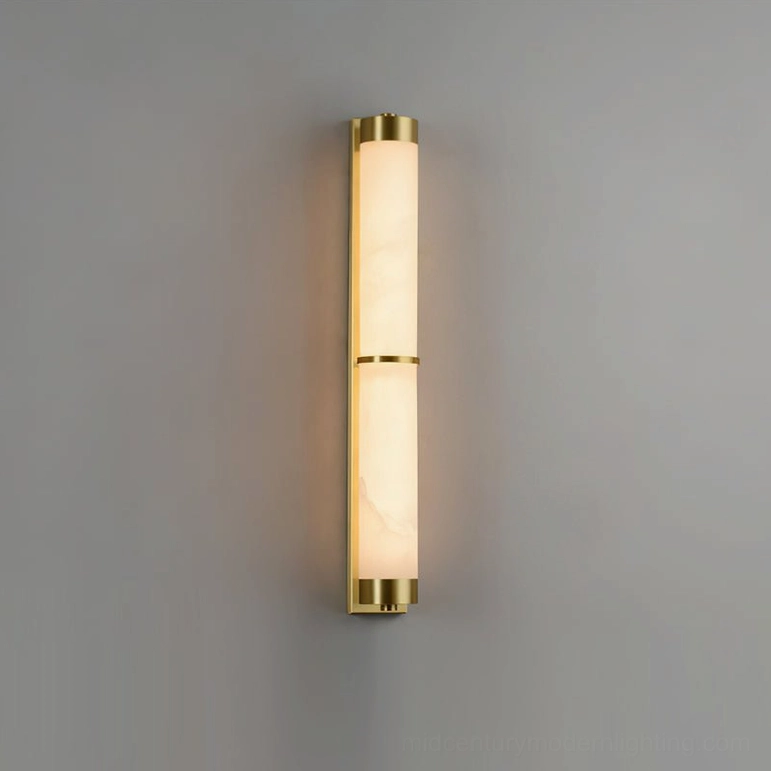 Long cylindrical alabaster wall sconce in studio setting with brass gold base and trim accents, three-section shade