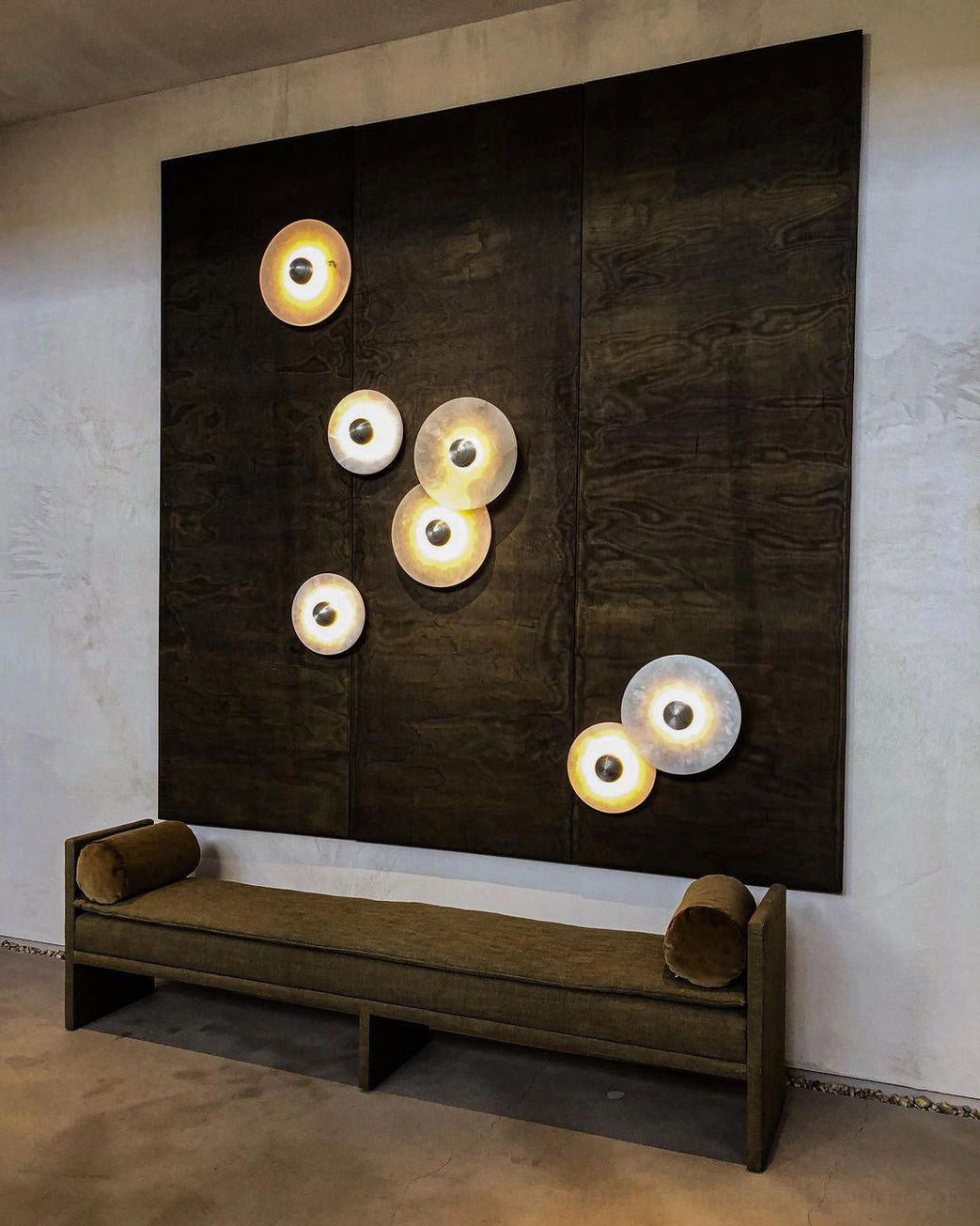 Luxury lounge area with clustered alabaster wall lights, dark wood accent wall, upholstered bench seating