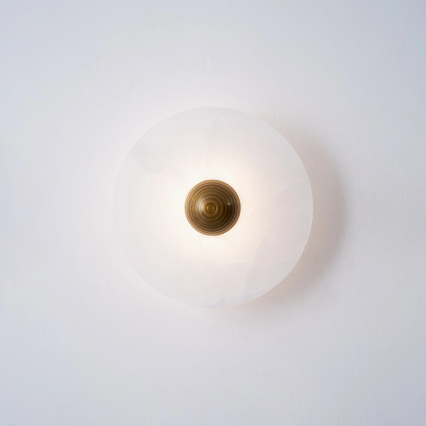Round alabaster wall light, gold finish metal frame, polished warm brass aesthetic, luxury lighting