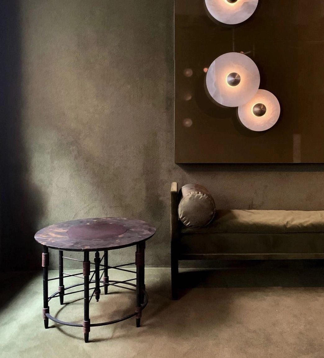 Wall-mounted alabaster light casting soft shadows, sculptural light pattern on white wall surface