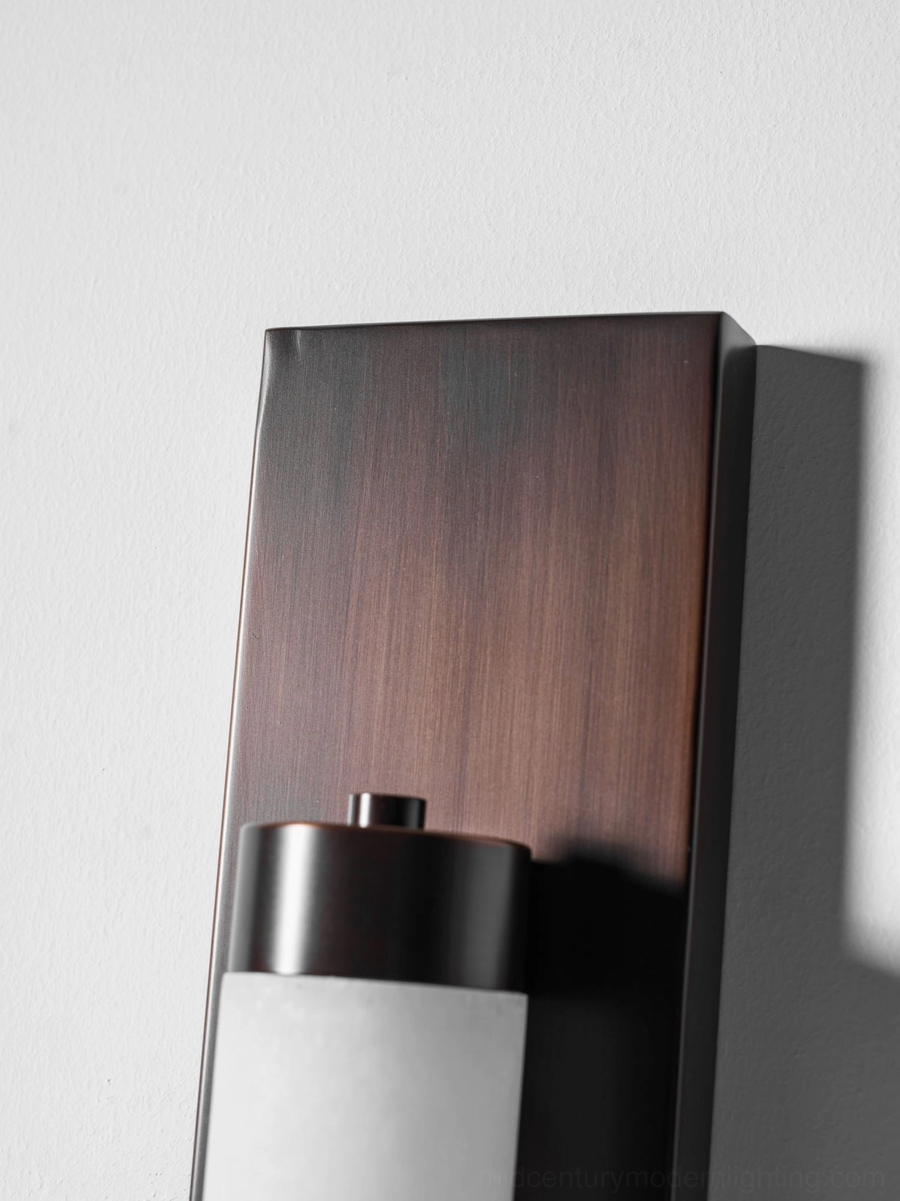 Columnar alabaster wall sconce mounted in neutral interior hallway corridor accent lighting