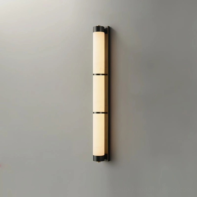 Alabaster cylindrical wall light with warm illuminated glow, black and white finish showing mid-century modern design aesthetic