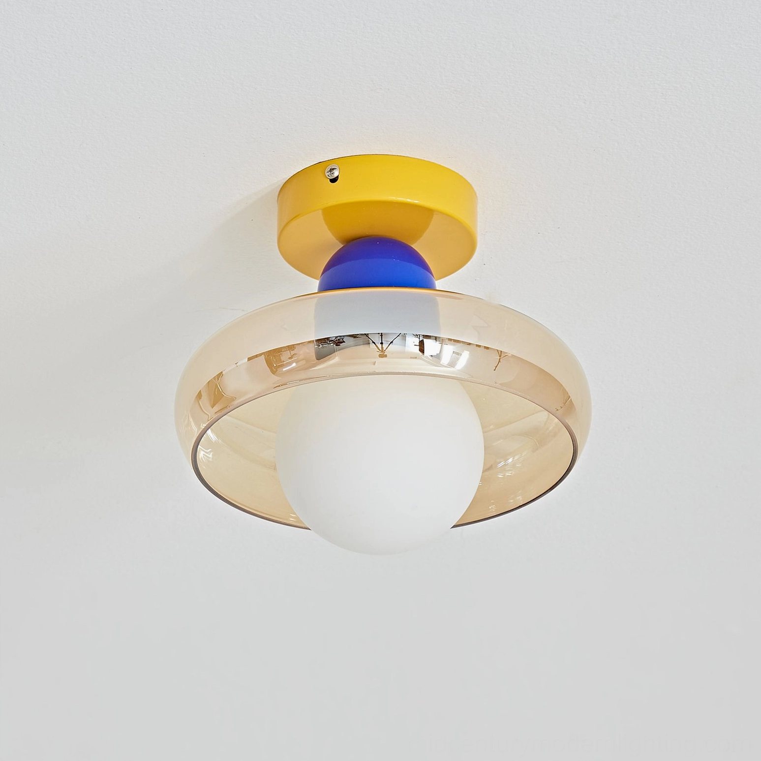 Yellow and blue geometric ceiling light detail against white studio background