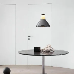 Modern minimalist dining area with Alain pendant light suspended over round marble table and contemporary dining chairs