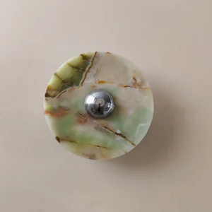 Alba round marble wall light frontal view mounted on beige wall demonstrating sculptural form and warm backlit glow