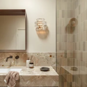 Albano wall sconce in luxury bathroom vanity setting, warm ambient lighting on neutral tile