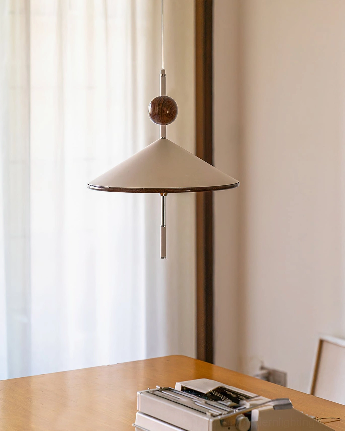 Alien pendant light installed above wooden desk in home office space with natural window light