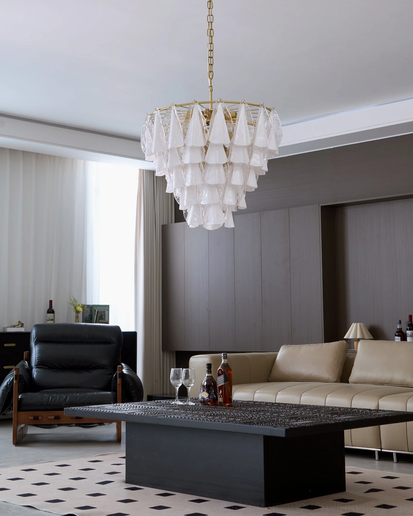 Alira tiered glass chandelier installed in high-end modern living room with neutral dark interior decor, overhead wide angle