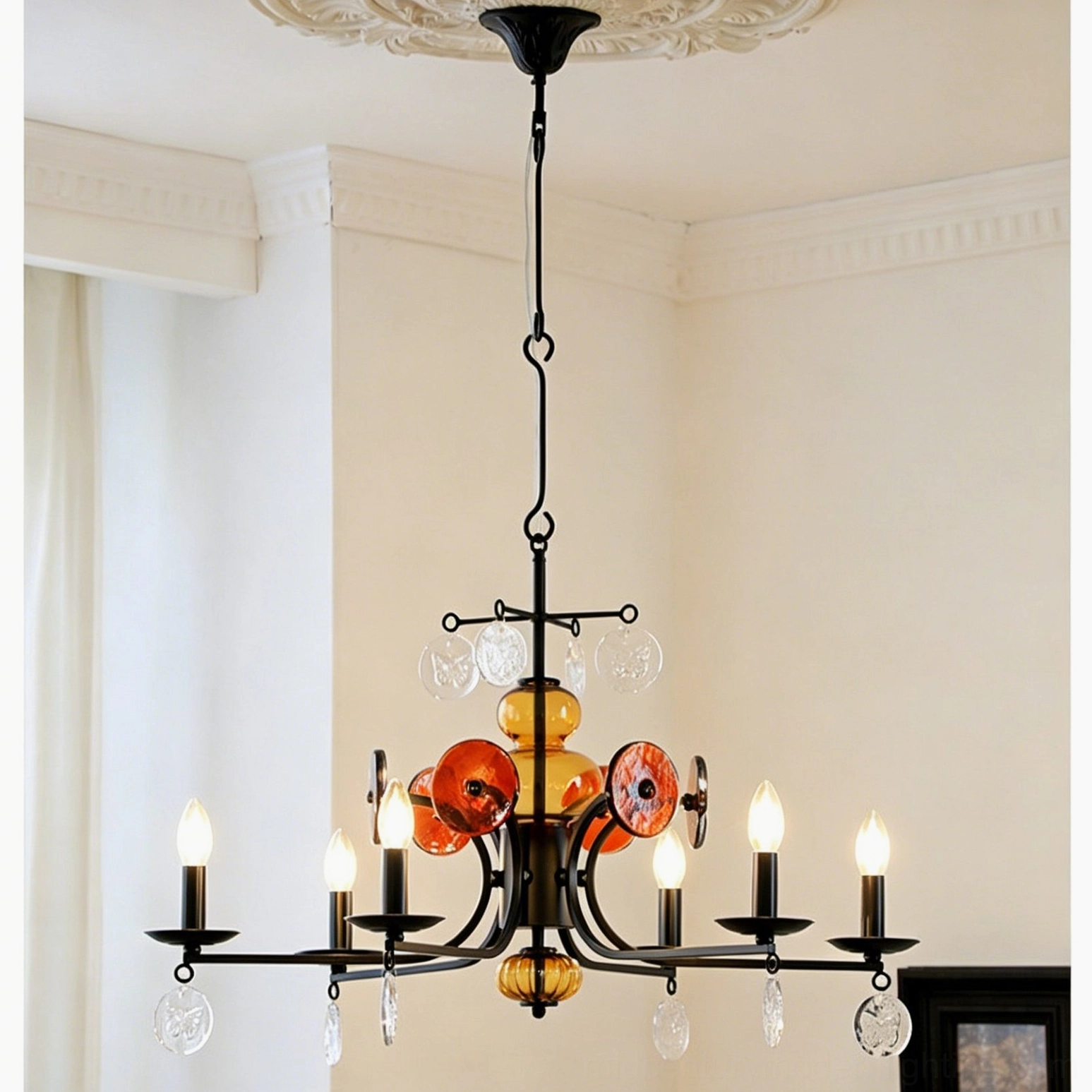 Close-up detail of Alistair chandelier showing illuminated candle bulbs and amber glass spheres with crystal pendants