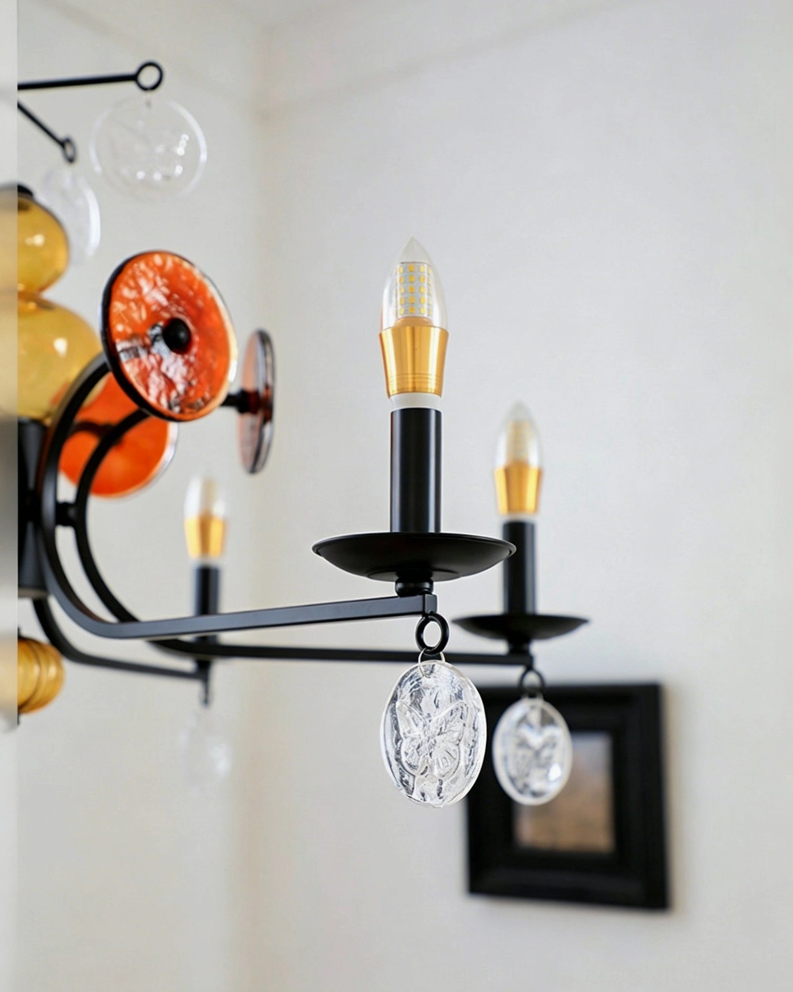 Alistair glass chandelier in bright room displaying black frame with warm amber glass accent lighting