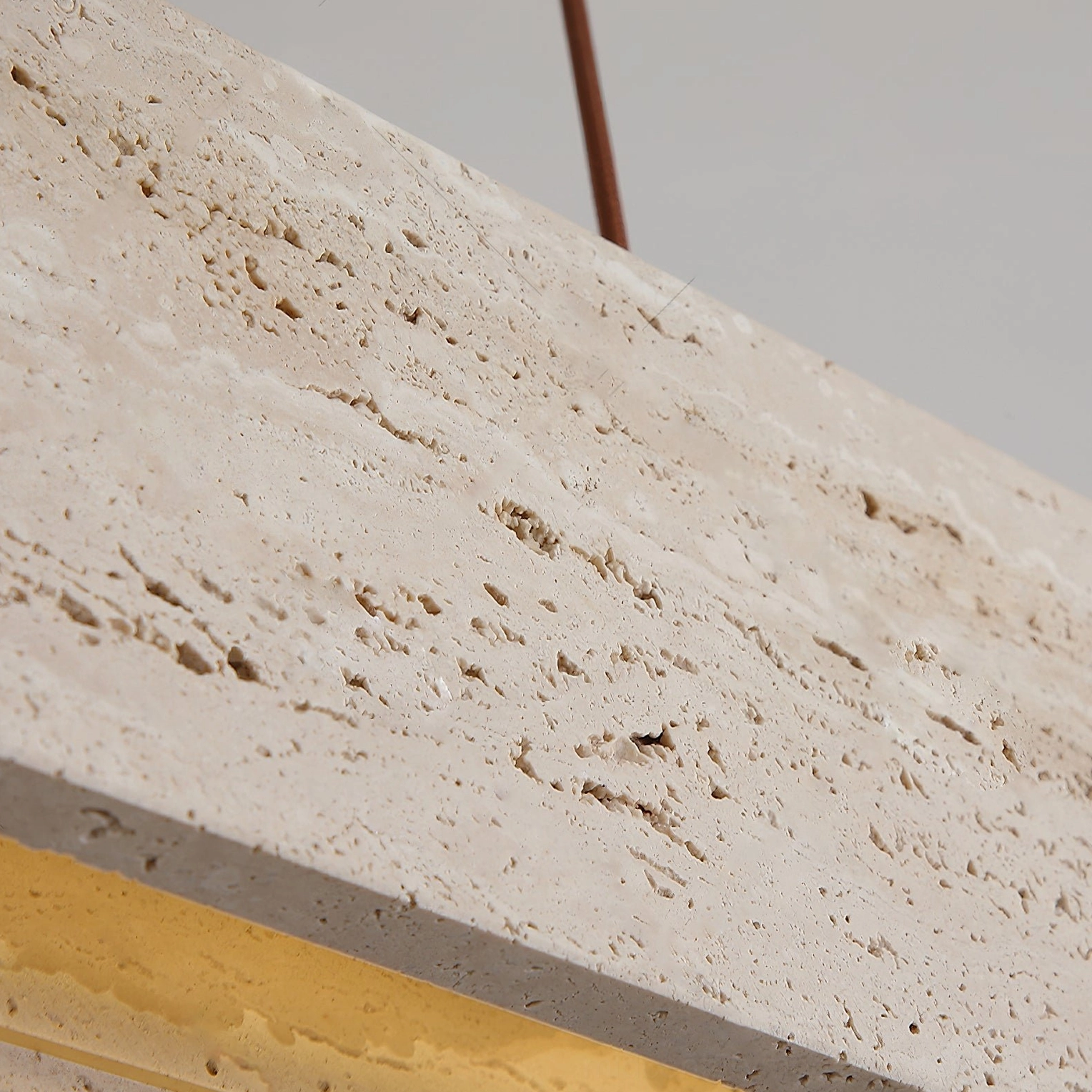 Macro detail of Aluet travertine stone component showing porous natural texture with warm LED beneath