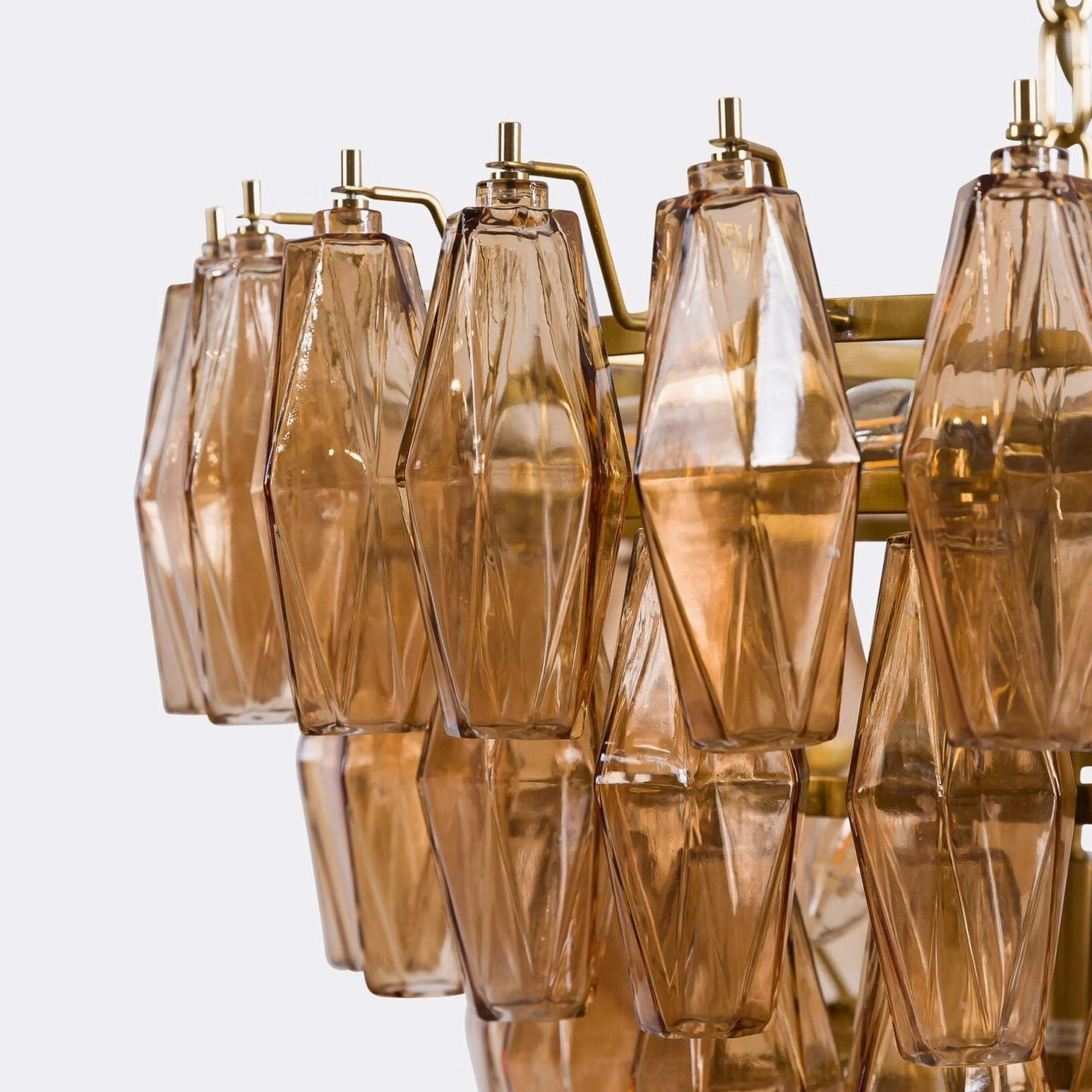 Macro close-up of amber crystal prism facets and brass metal fixture details