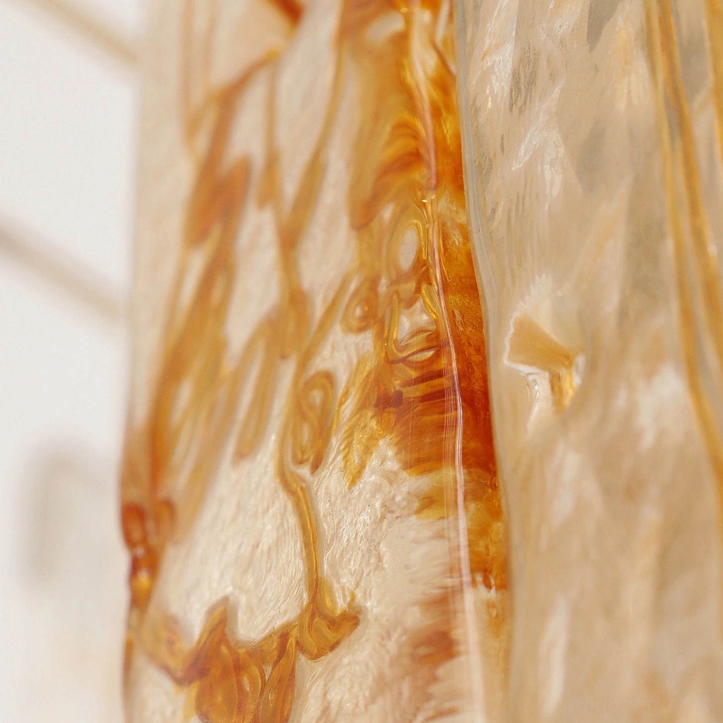 Macro texture close-up of thick amber glass with natural swirls and artistic surface variations in soft light