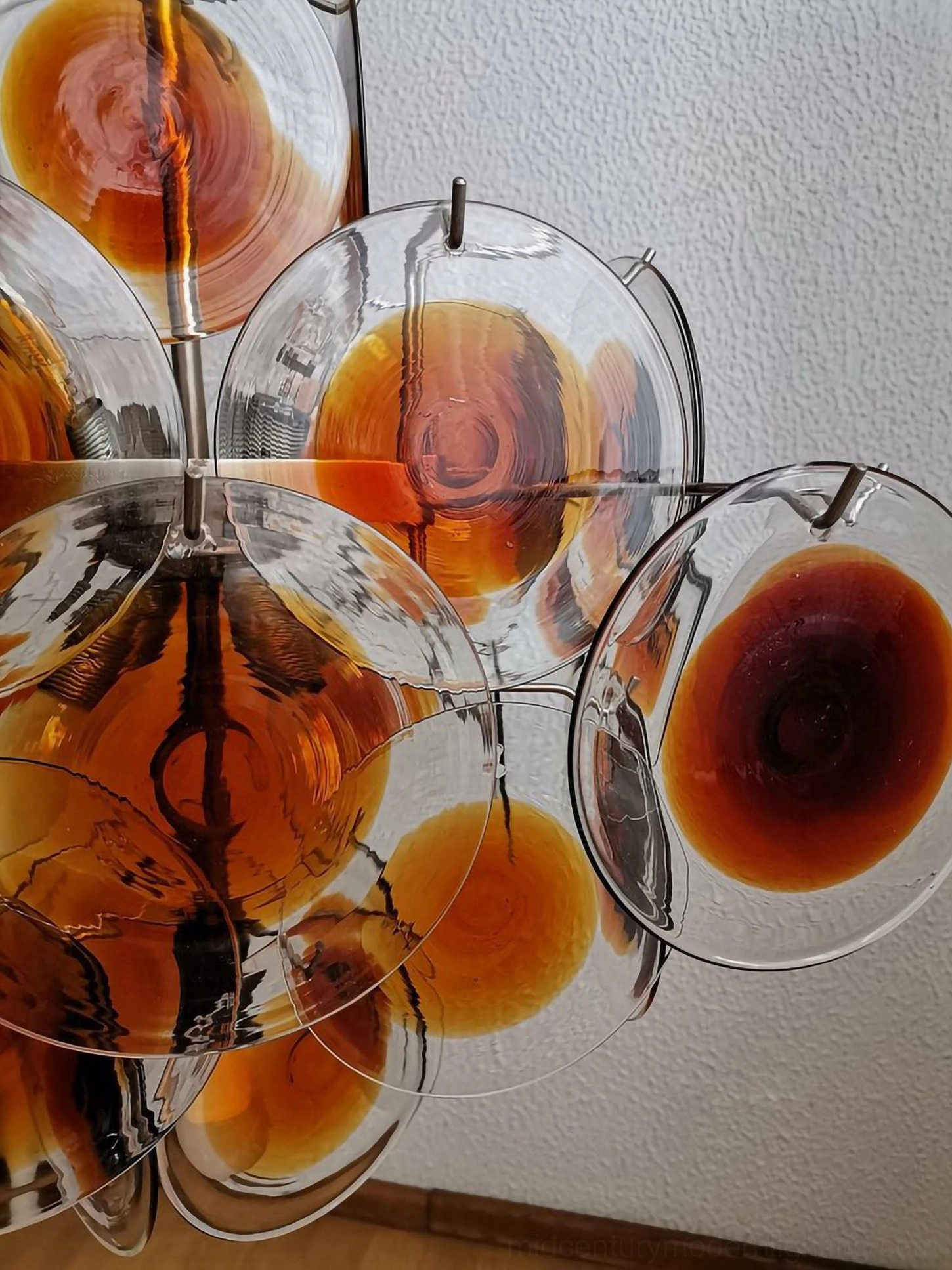 Close-up angle of swirled amber glass with polished metal fixtures showing artisanal craftsmanship detail