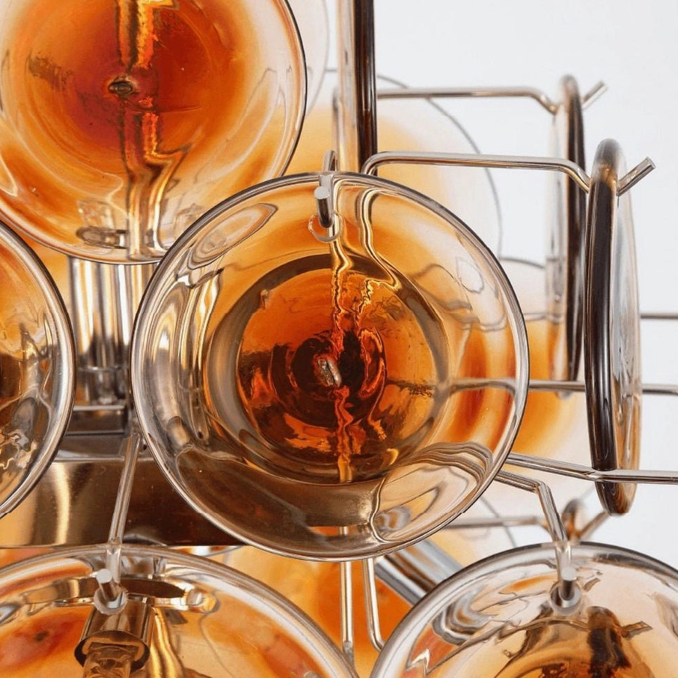 Overhead close-up of curved amber glass discs showing hand-blown texture and metal mounting brackets