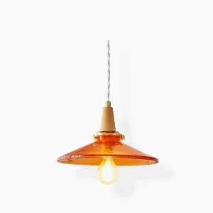 Amber glass pendant lamp with disc-shaped shade, brass hardware, and twisted fabric cord on white studio background - front view of mid-century modern ceiling light