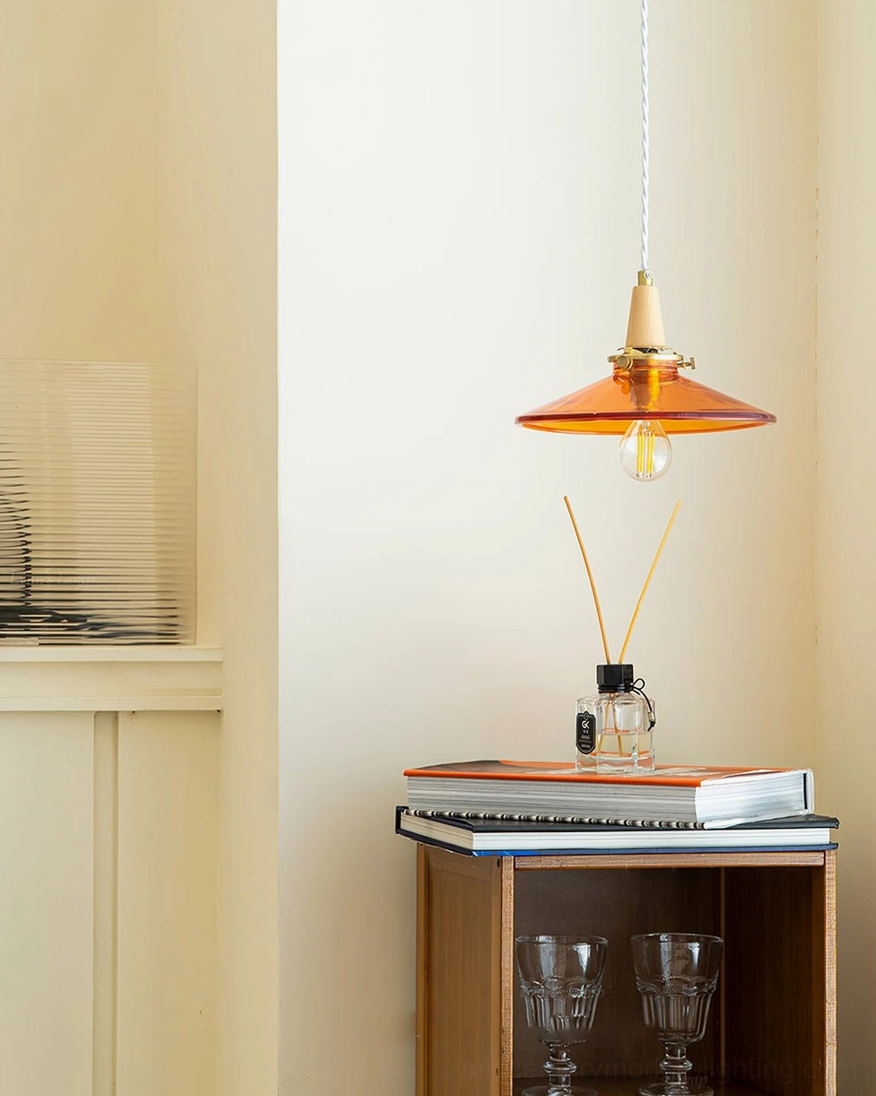 Amber glass pendant hanging above side table with reed diffuser - minimalist mid-century modern bedroom or study lighting