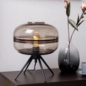 Amber tinted refraction glass table lamp displayed on side table with floral decor in modern home interior