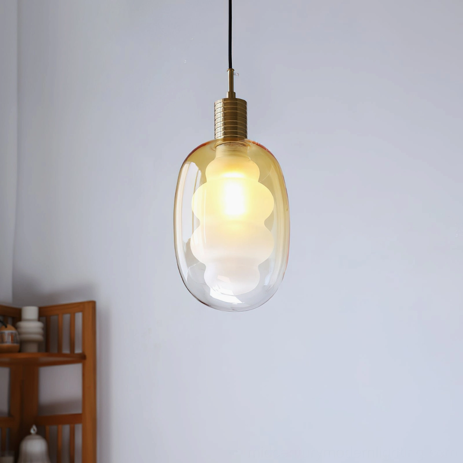 Amber gradient glass pendant light with brass accents, wooden display shelf, contemporary setting