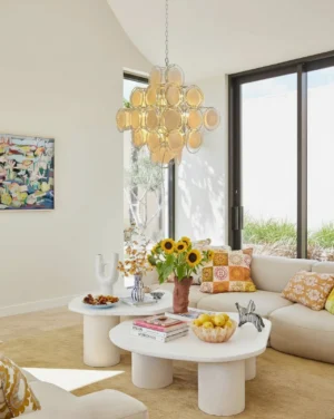 Amber tinted glass medallion chandelier glowing in modern living room with sectional sofa, warm yellow glass discs