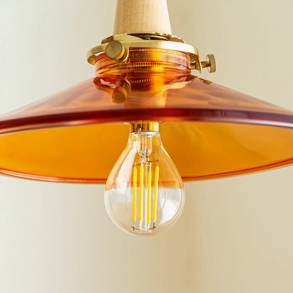 Amber glass pendant light fixture detail shot showing brass hardware, wood accents, and prismatic glass construction