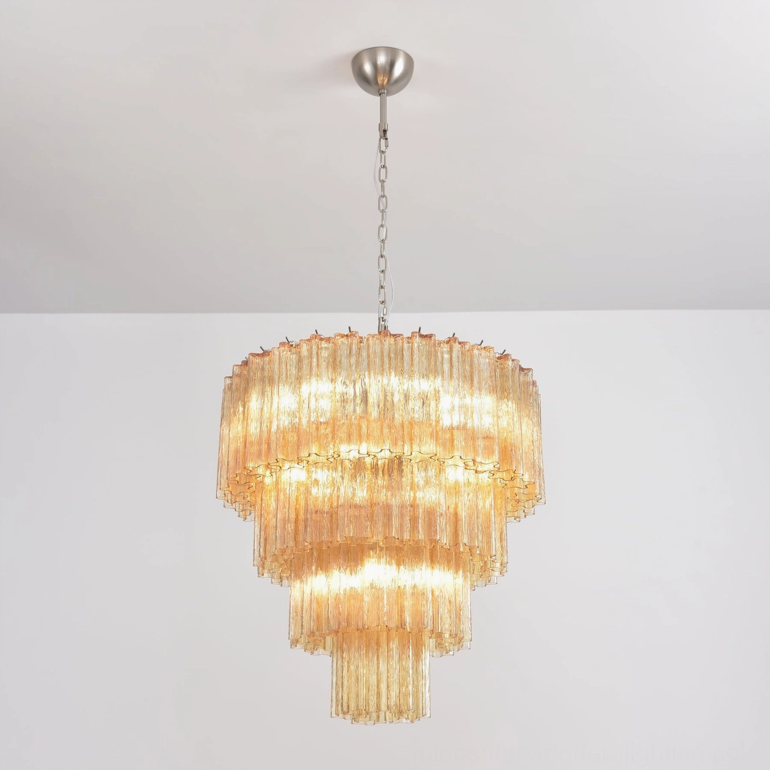 Amber tiered glass chandelier three-quarter overhead angle warm illuminated modern lighting