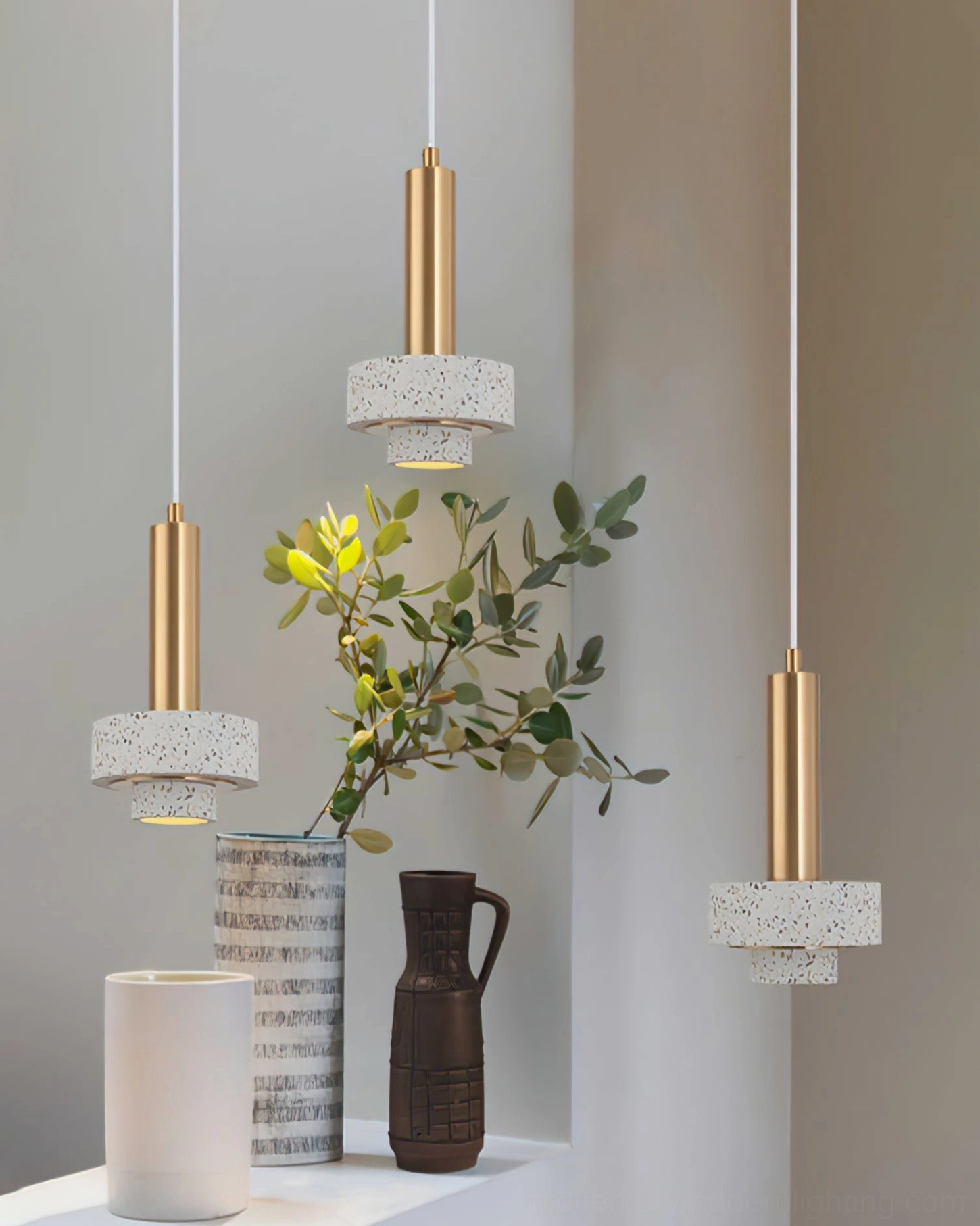 White terrazzo pendant lamps with brass fixtures in home display area with minimalist aesthetic