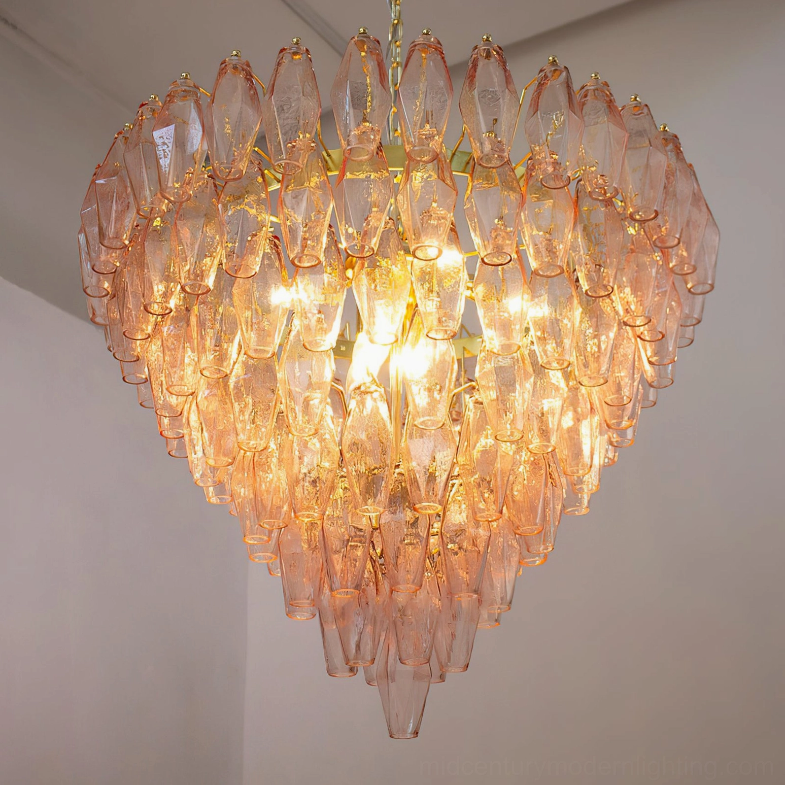 Close-up of amber and gold Ametista glass chandelier illuminated showing warm glowing orange glass with polyhedral tile structure