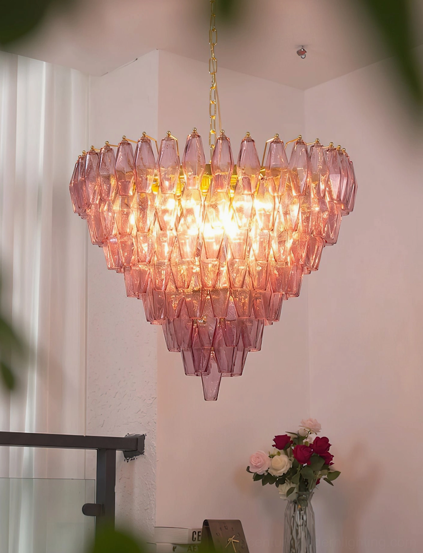 Low-angle view of Ametista glass chandelier installed in home stairwell with warm glowing light and architectural presence