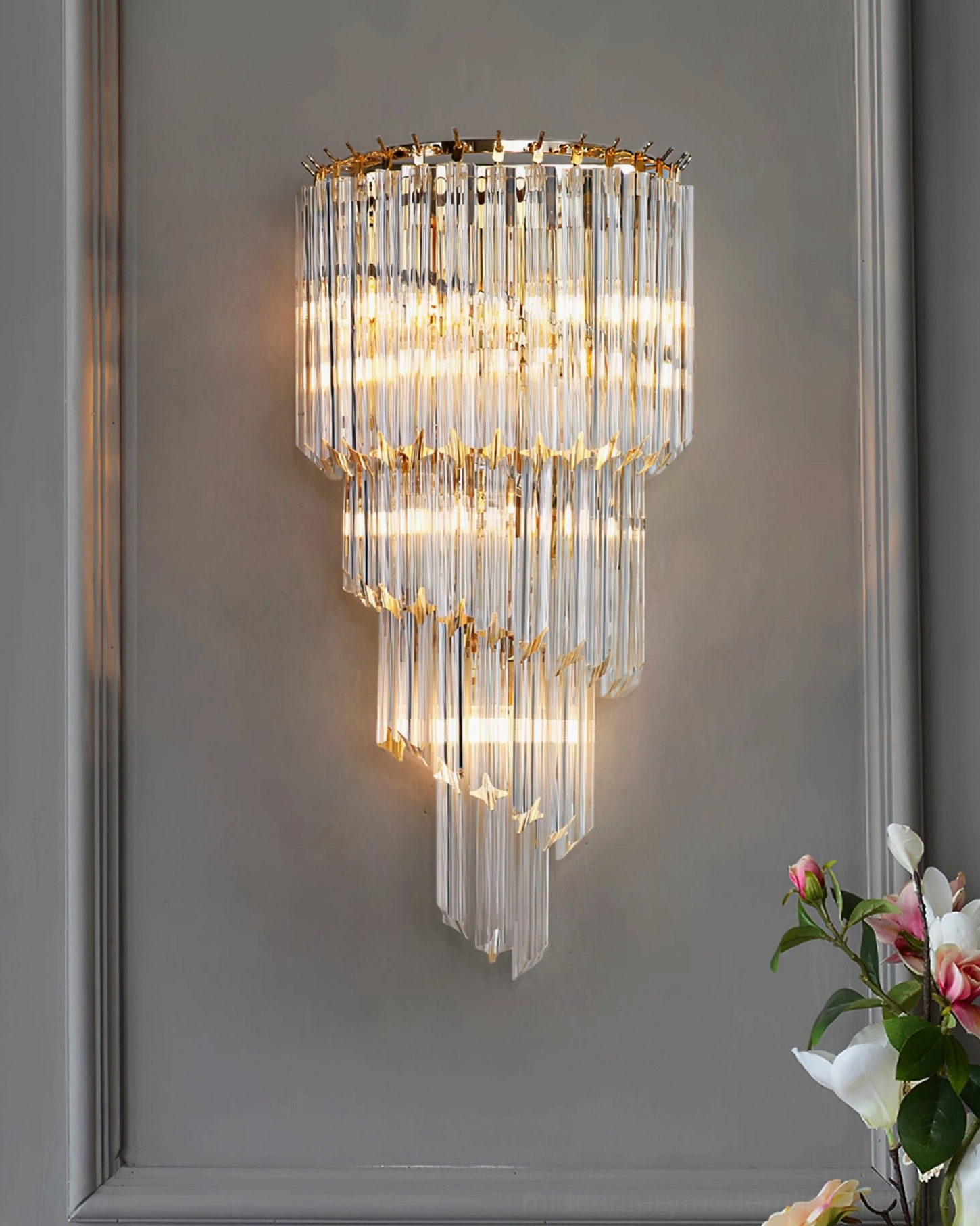 Crystal wall sconce installed beside decorative frame and botanical accents, luxury upscale interior setting