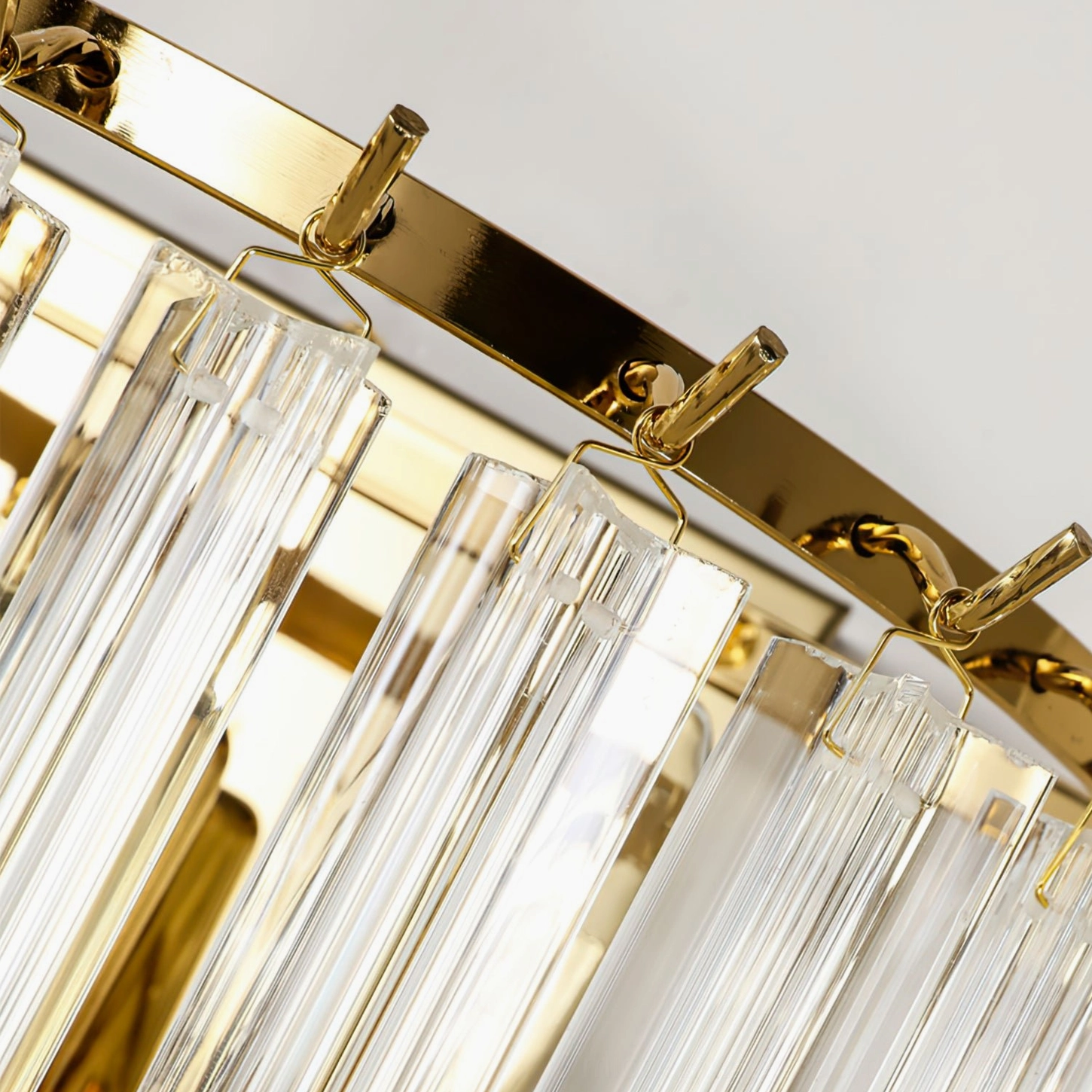 Close-up detail of polished gold metal clips and hanging crystal glass rods, showing hardware craftsmanship