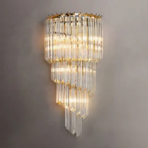 Tiered crystal wall sconce illuminated with warm light on dark gray textured wall, showing light diffusion through crystal rods