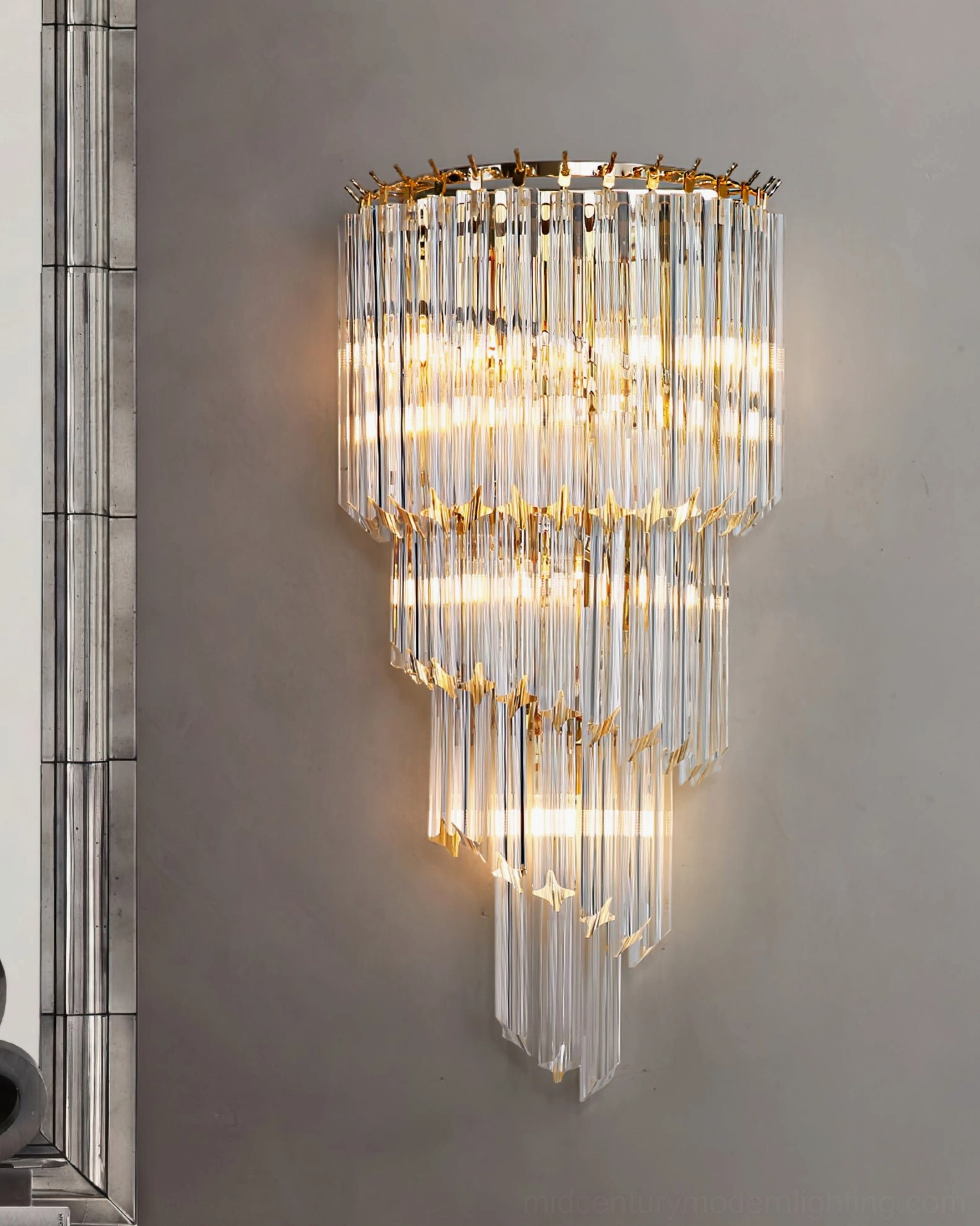 Glowing cascading crystal wall sconce on vertical metal trim wall, warm ambient illumination