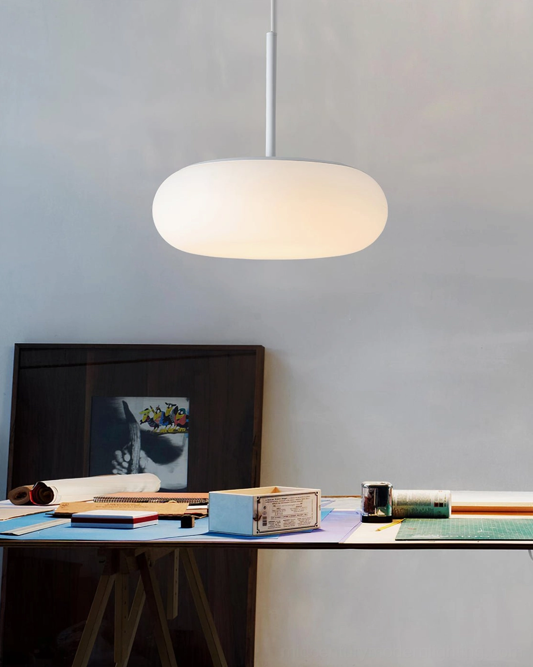 Amor white pendant lamp illuminating modern home office workspace, clean minimalist setup with focused task lighting