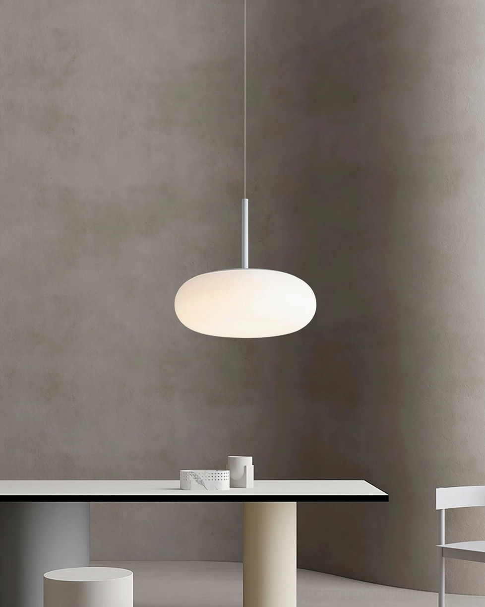 Amor white oval pendant lamp in minimalist studio apartment, showcasing sleek monochrome Scandinavian design aesthetic