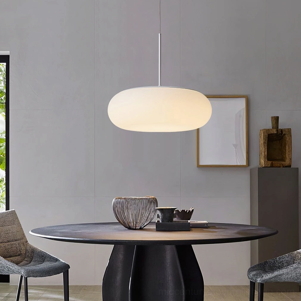 Amor pendant lamp installed above dining table in modern dark-toned dining room, showing warm light diffusion through frosted glass