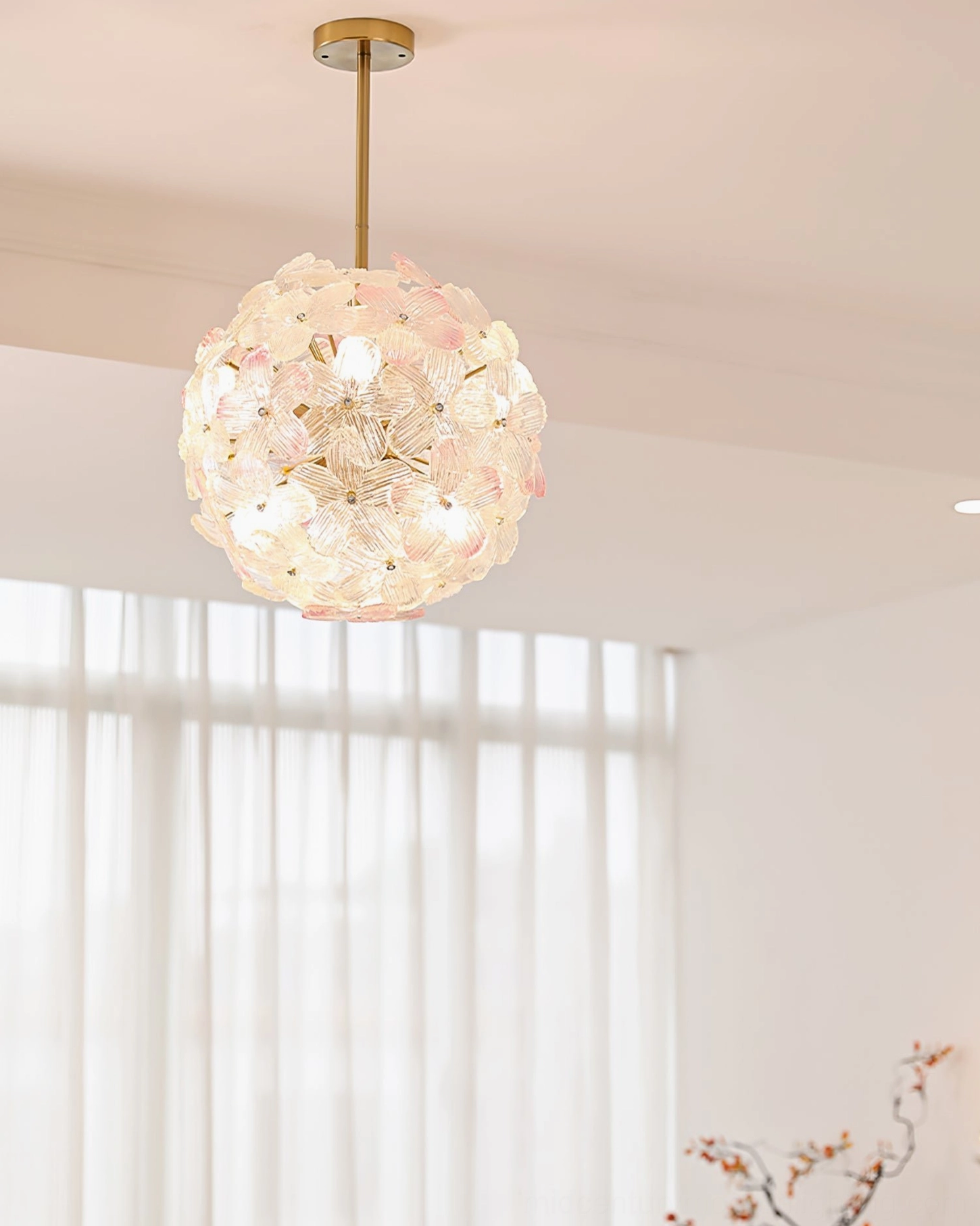 Anan Floral Pendant Light eye-level front view, clear glass flower petals with gradient pink, gold metal rod, sheer curtains