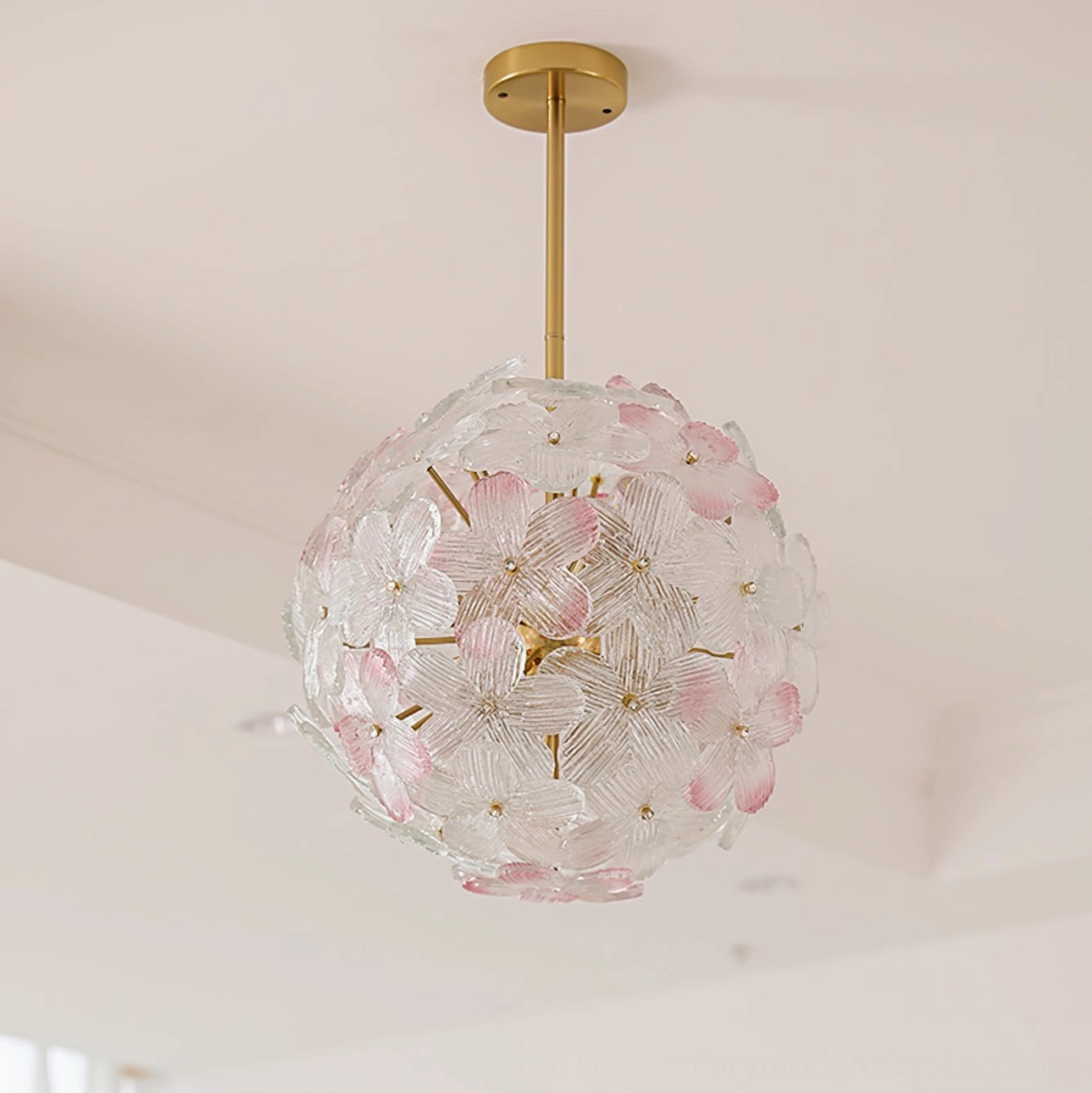 Anan Floral Chandelier illuminated in minimalist living room with cream interior, showing soft pink glass flowers and gold metal suspension